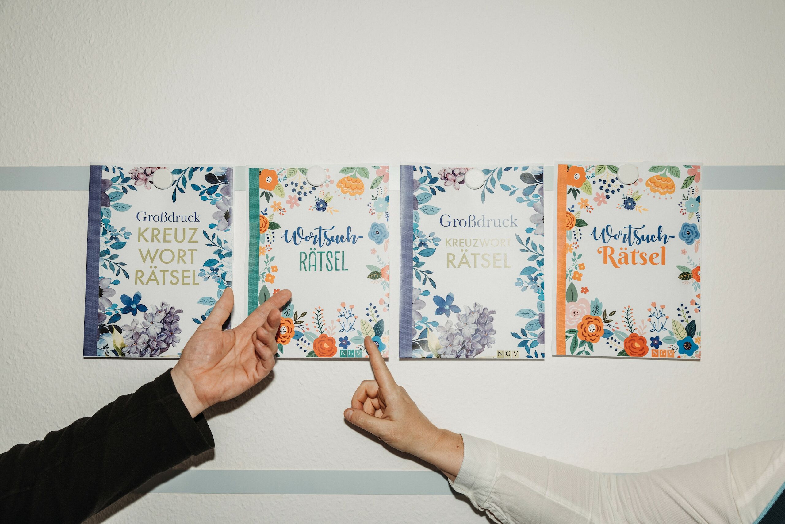 Zwei Hände zeigen auf vier unterschiedliche Coverentwürfe eines Buches