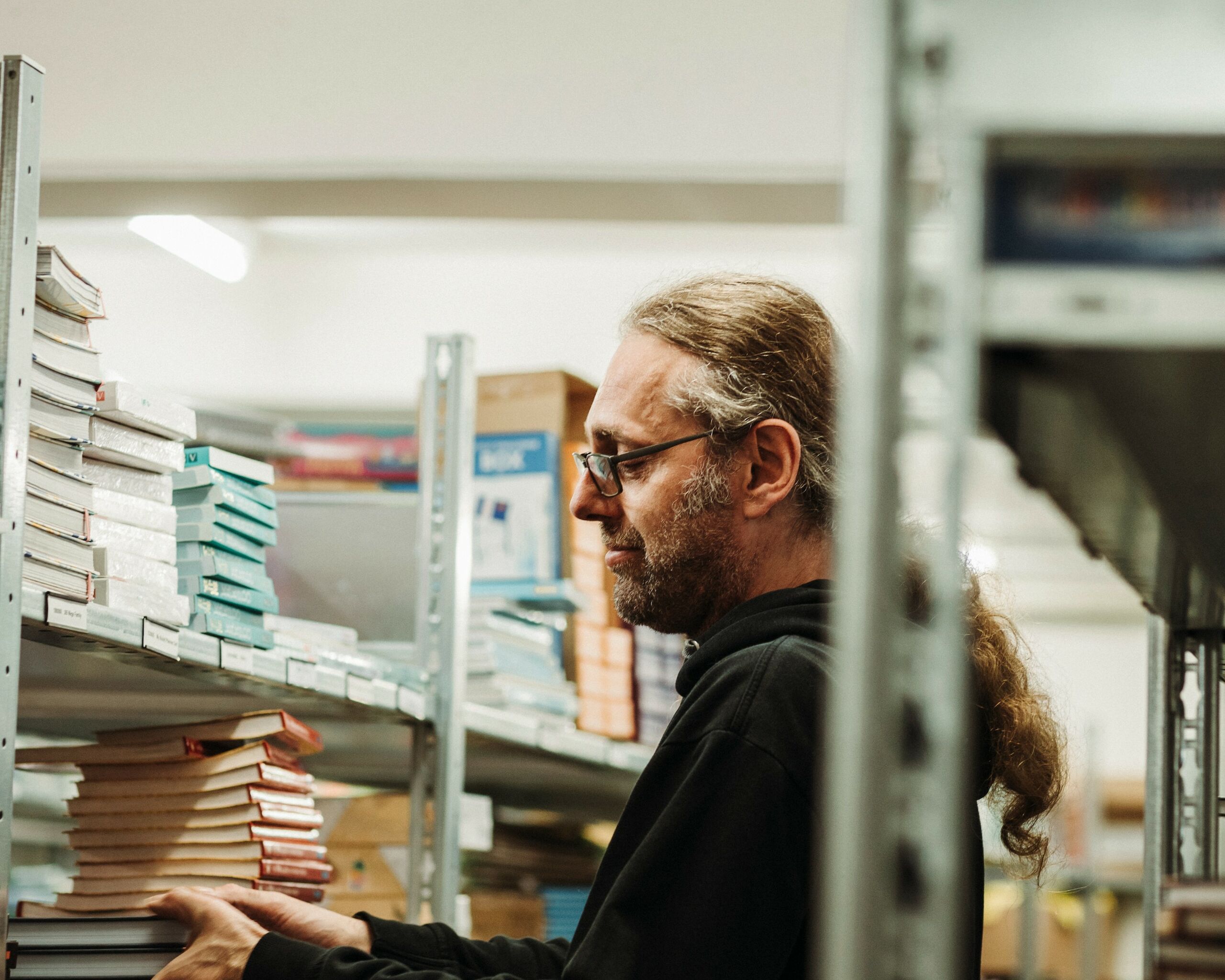 Ein Mitarbeiter legt Bücher in ein Lagerregal