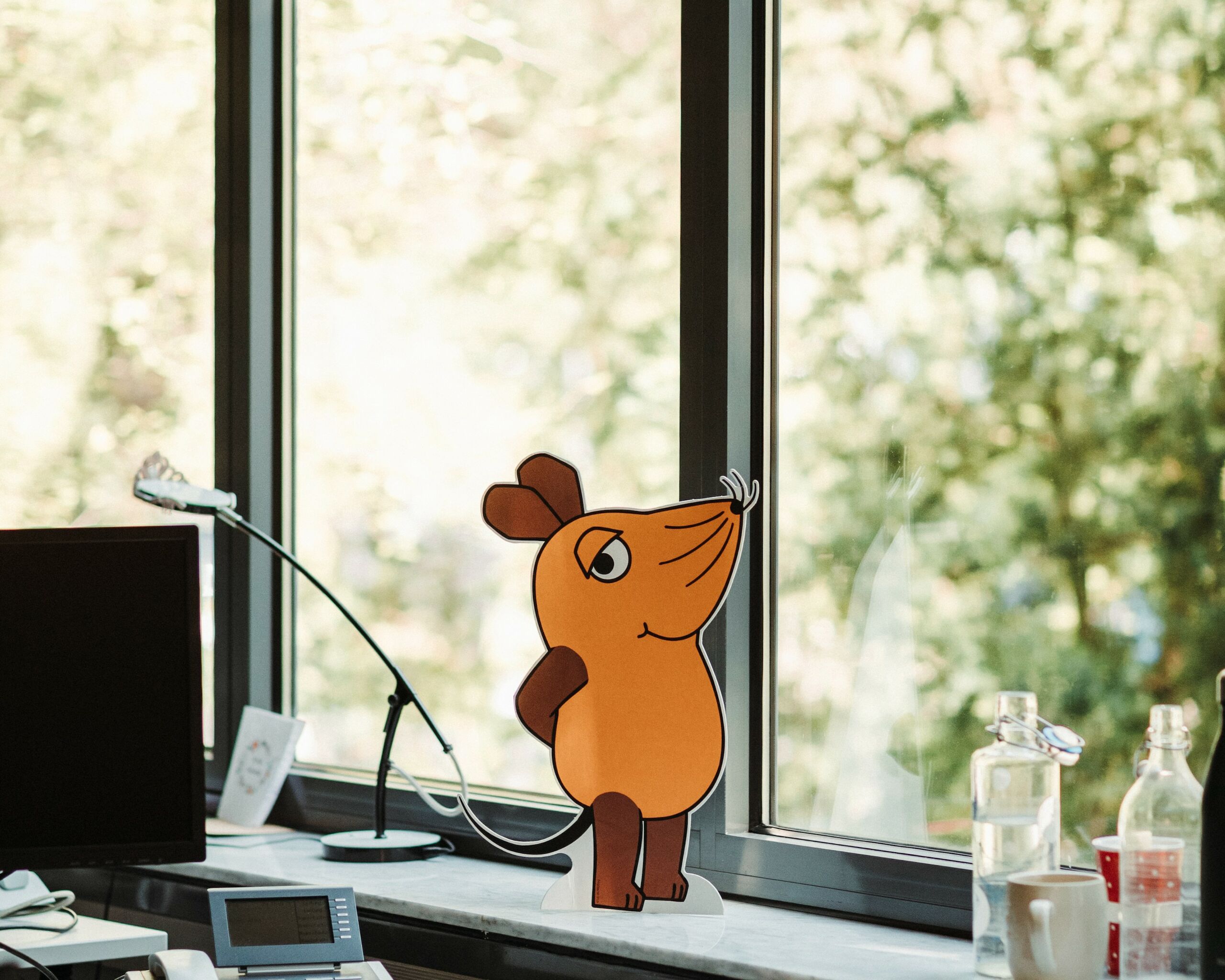 Die Maus vor einem Bürofenster