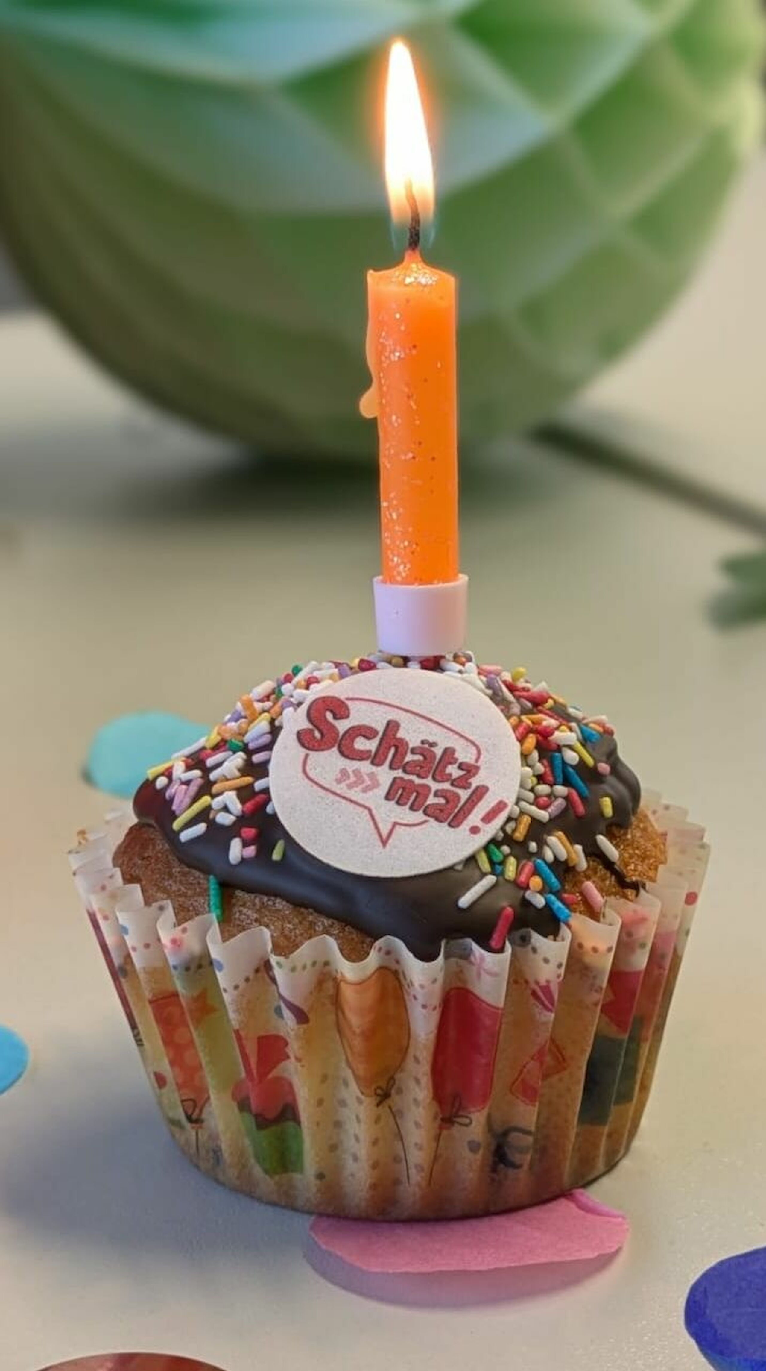 Foto eines Muffins mit Schätz mal! Logo und einer Kerze